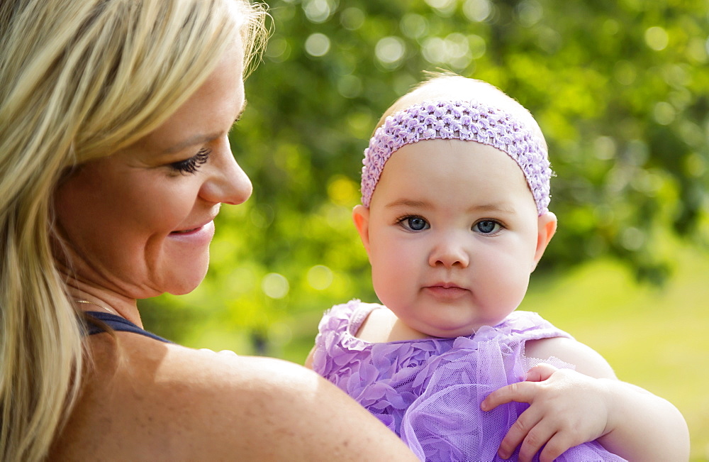 A mom holding her baby daughter while enjoying time in a city park during a beautiful fall afternoon, Edmonton, Alberta, Canada