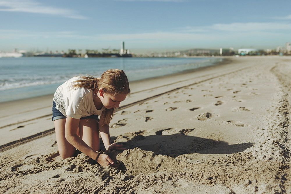 A girl playing in the sand at the beach, Long Beach, California, United States of America