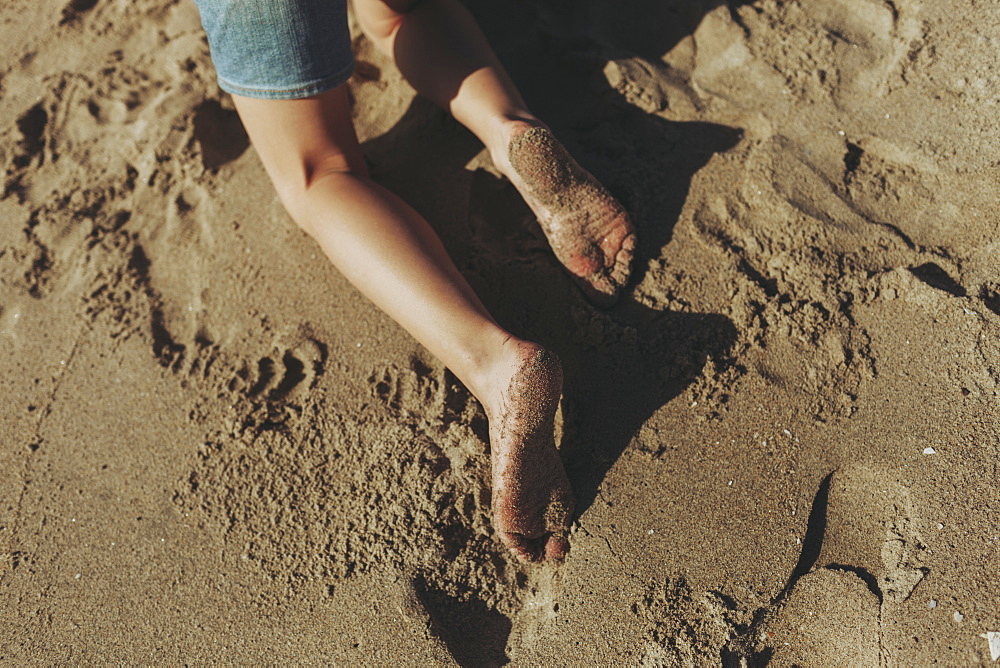 A child's wet feet covered in sand, Long Beach, California, United States of America