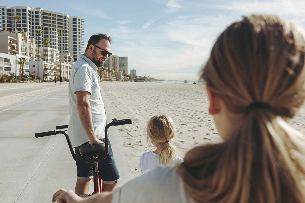 A father and daughters riding bikes at Long Beach, Los Angeles, California, United States of America