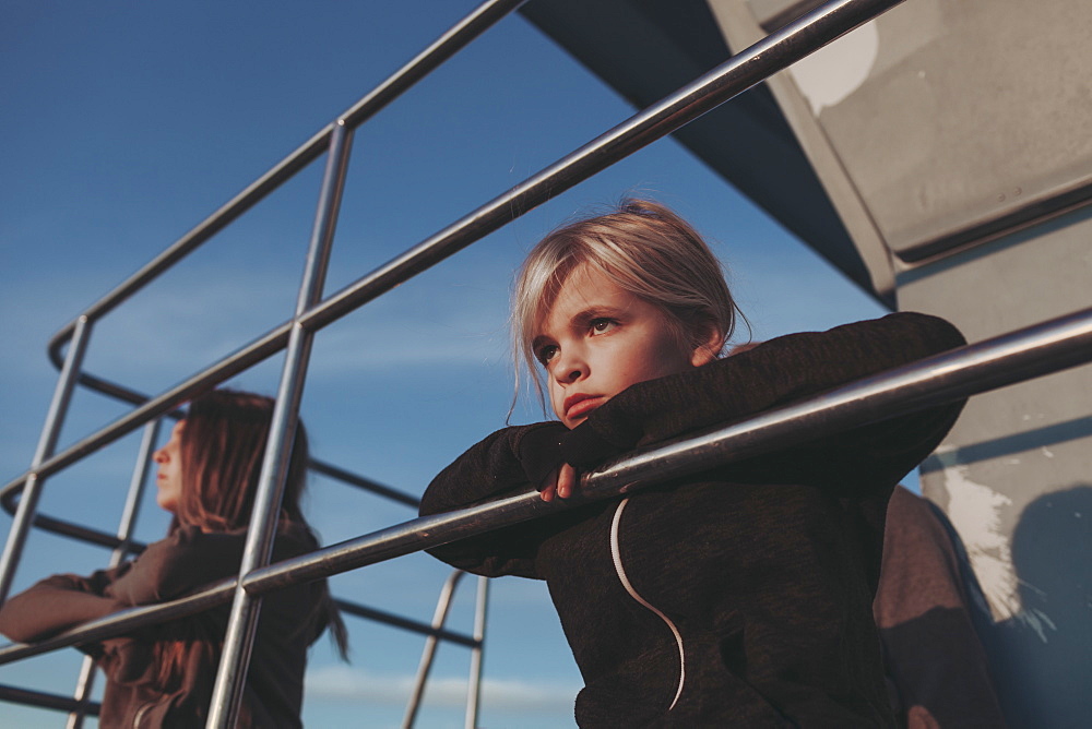 Two girls sit on a lifeguard station at dawn looking out to the ocean, Long Beach, California, United States of America