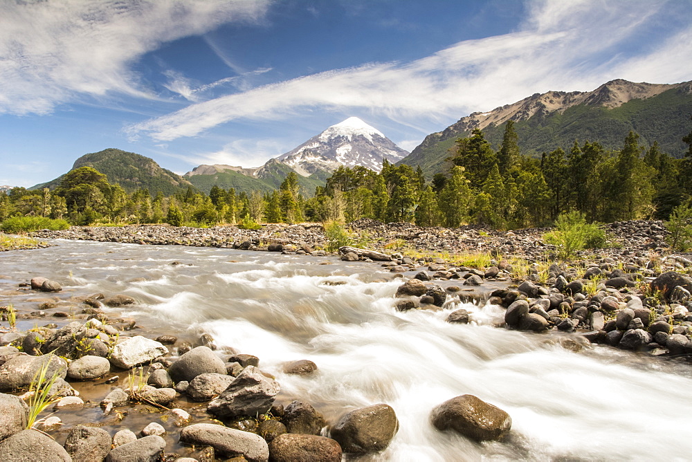 A mountain river with snow-capped volcano in the distance, Neuquen, Argentina