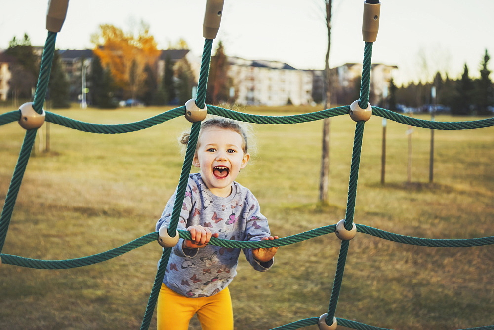 A young girl climbing on a piece of playground equipment on a warm autumn evening at sunset, Edmonton, Alberta, Canada