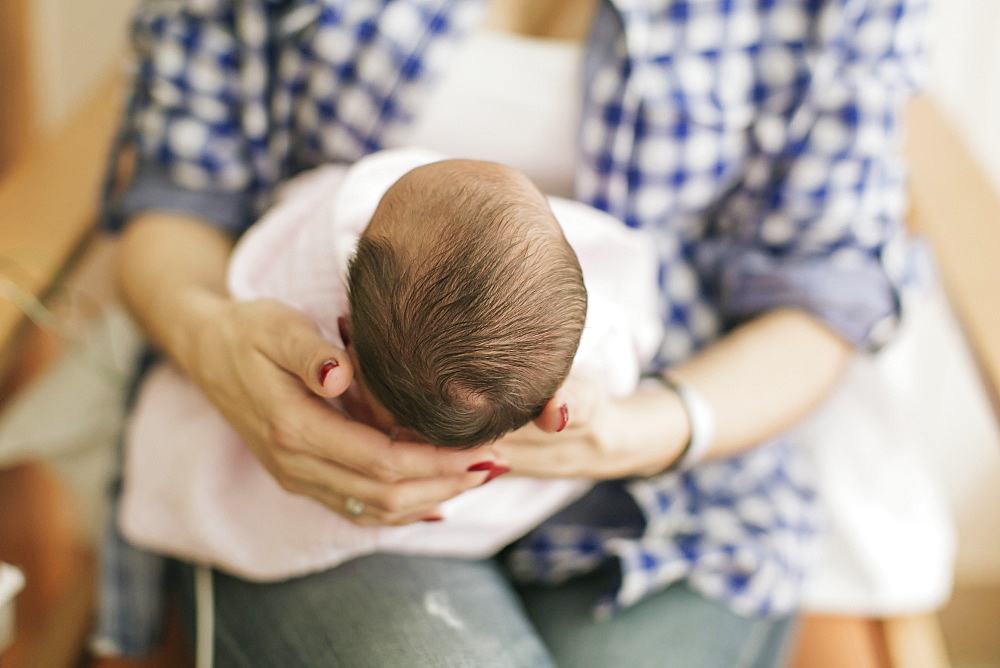 Newborn baby in mother's arms in the Neonatal Intensive Care Unit, Surrey, British Columbia, Canada