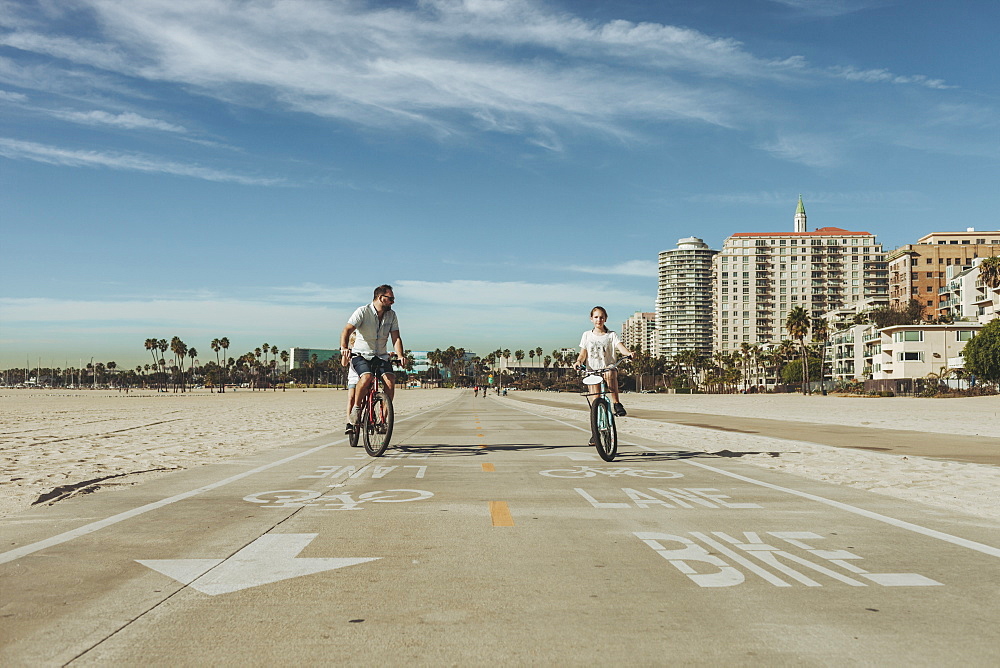 A father and daughter riding bikes at Long Beach, Long Beach, California, United States of America