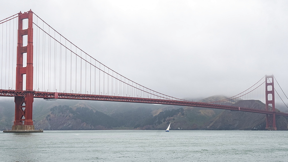 Golden Gate Bridge on a cloudy day with a sailboat on the water below, San Francisco, California, United States of America