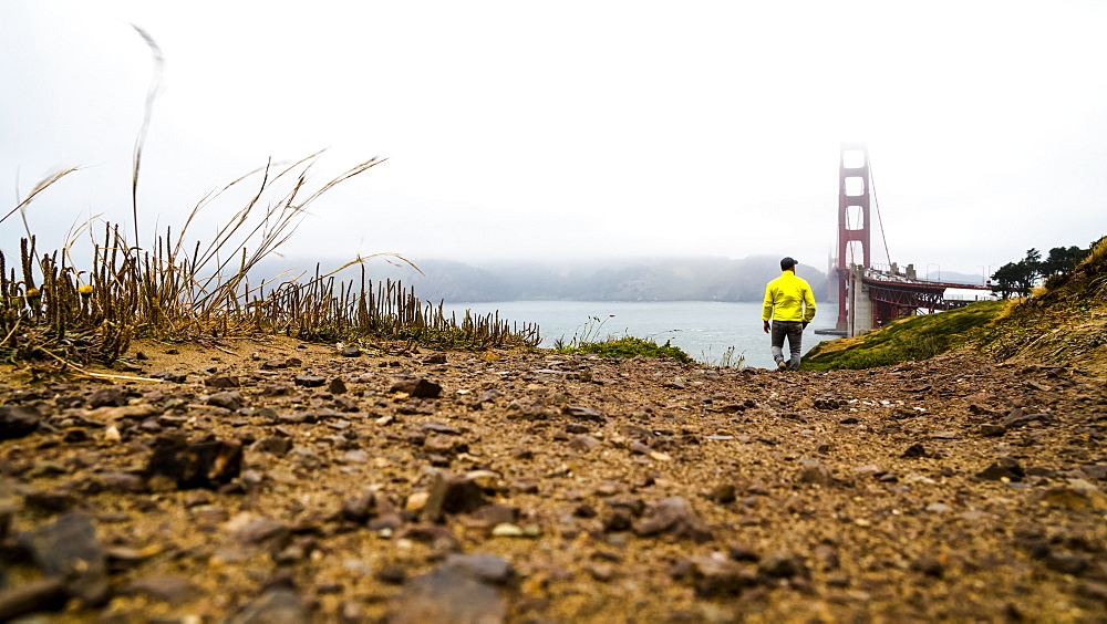 A man walking near the Golden Gate Bridge on a foggy day, San Francisco, California, United States of America