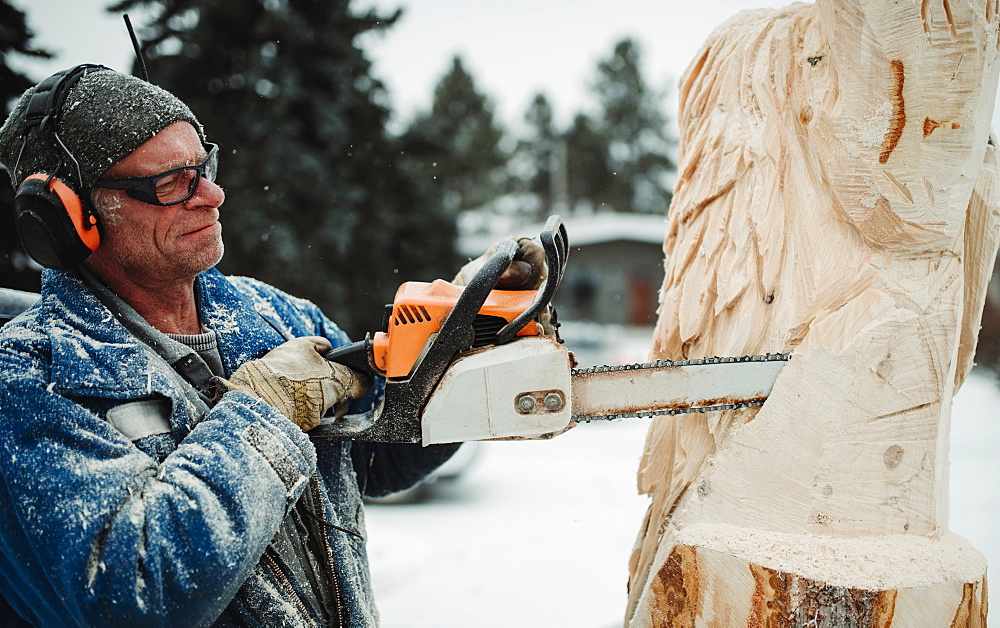 Artist carving a wood sculpture with chainsaw, Edmonton, Alberta, Canada