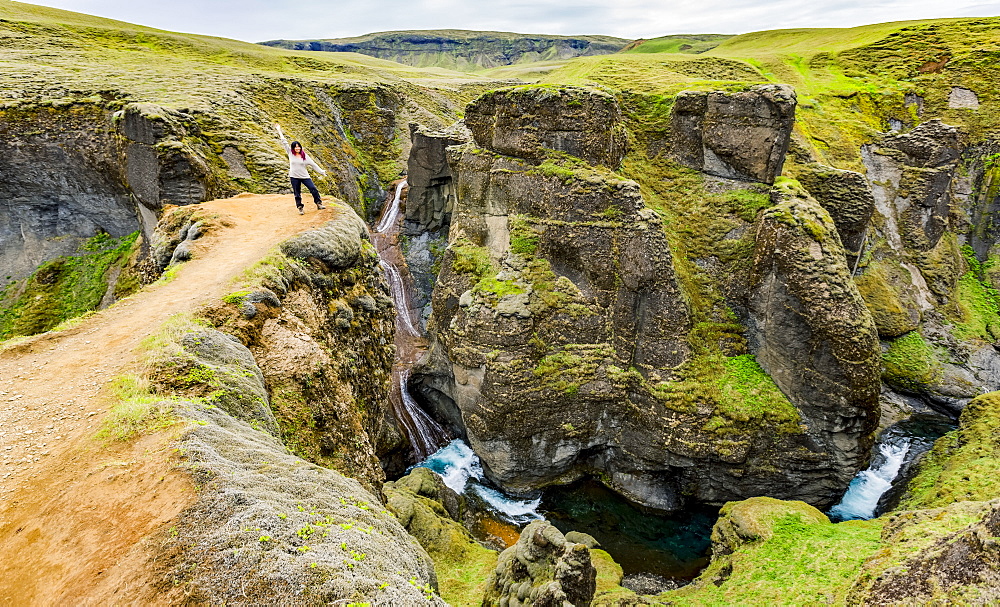 A female tourist stands on a cliff viewpoint in the picturesque valley of Fjadrargljufur in Southern Iceland, Iceland