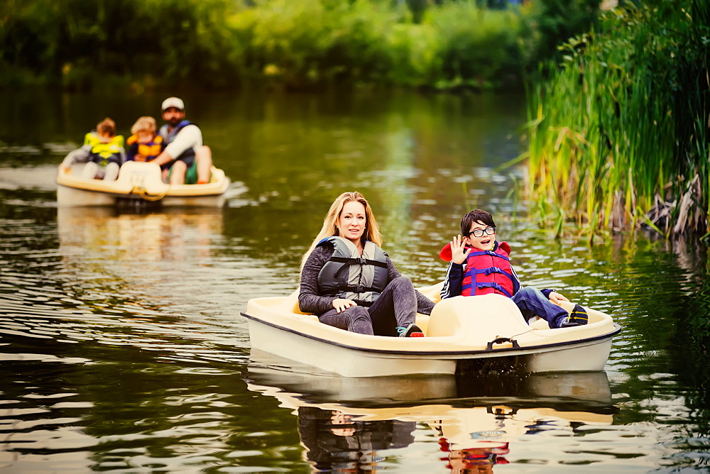 A mother and father take their three sons paddle boating on a lake in a city park, Edmonton, Alberta, Canada