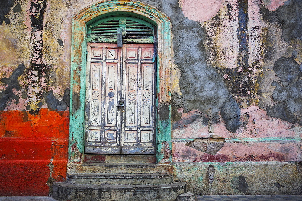 Worn and weathered facade of a building with peeling paint and double doors, Nicaragua