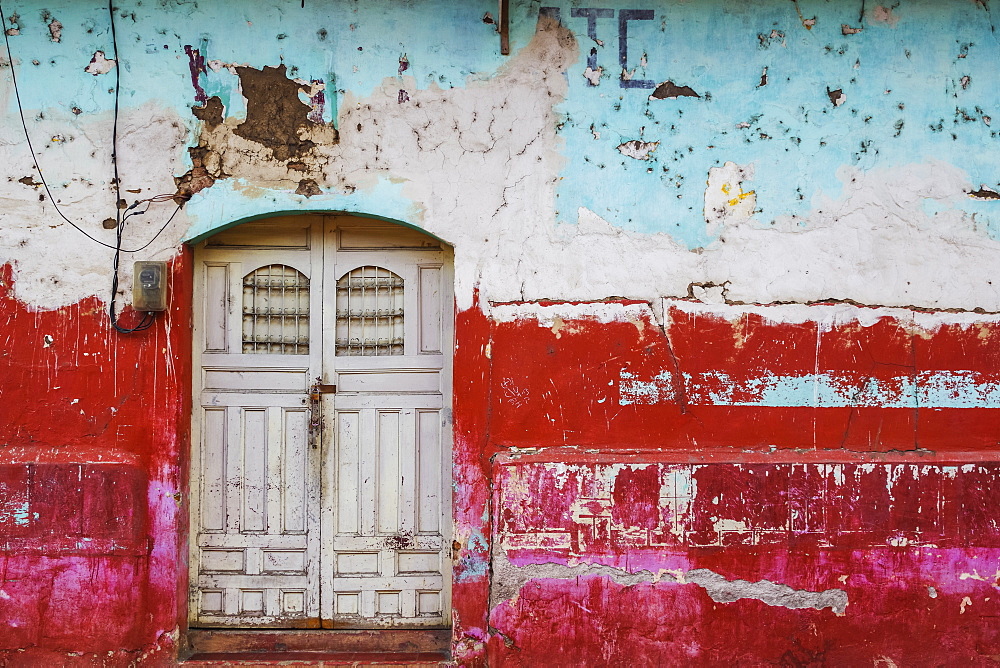 Worn and weathered facade of a building with peeling paint and double doors, Nicaragua