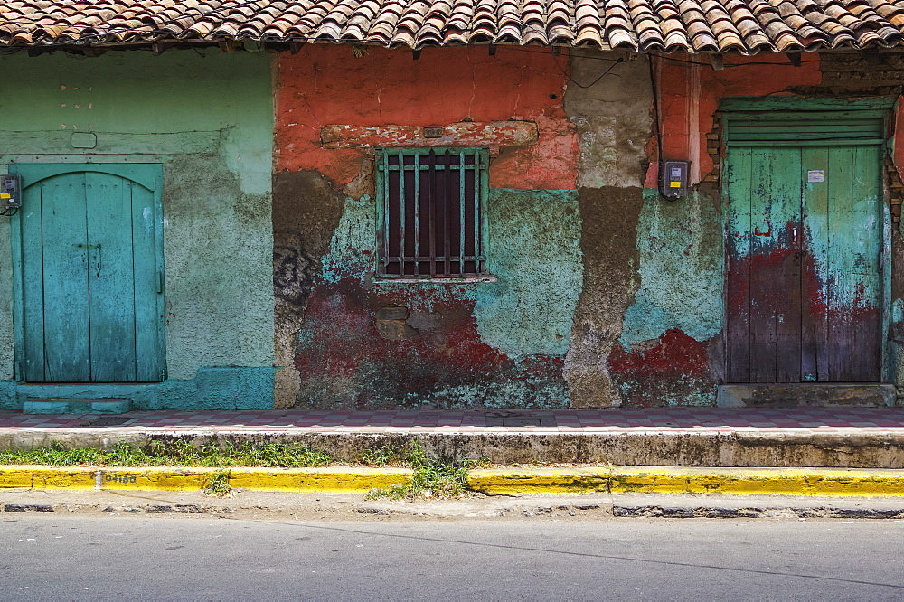 Worn and weathered facade of a building with peeling paint and double doors, Nicaragua