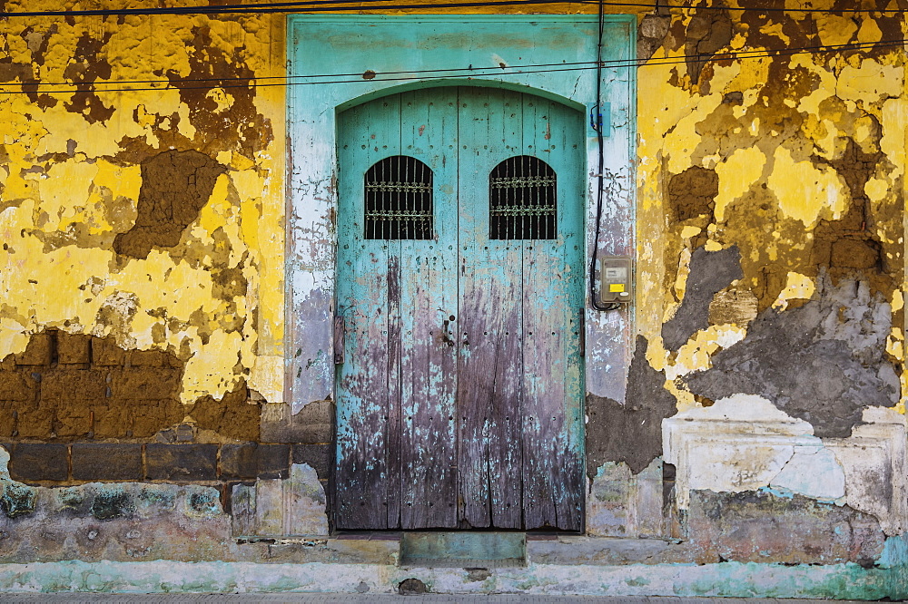 Worn and weathered facade of a building with peeling paint and double doors, Nicaragua