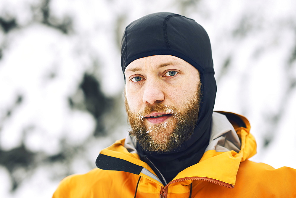 Portrait of a man with a frosty beard wearing a head covering against a snowy background, British Columbia, Canada