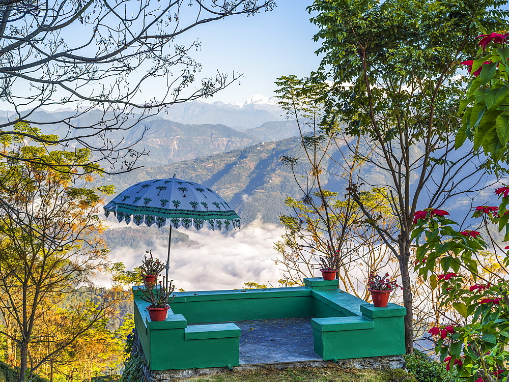 A small green terrace with umbrella decorated with plants and overlooking the mountains and valley, West Bengal, India