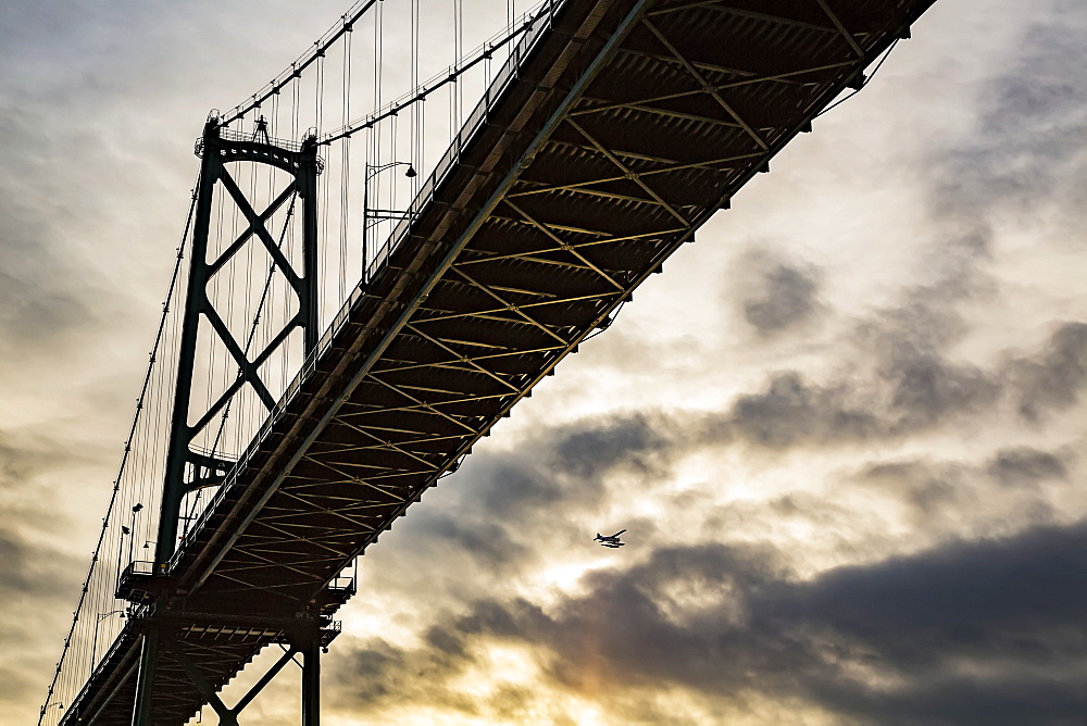 Low angle view of a bridge at sunset with an airplane flying in the distance, Vancouver, British Columbia, Canada