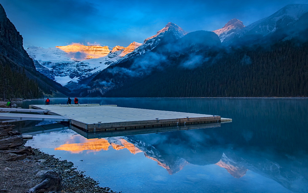 Peaks of the Rocky Mountains illuminated by sunlight and reflected in Lake Louise, Lake Louise, Alberta, Canada