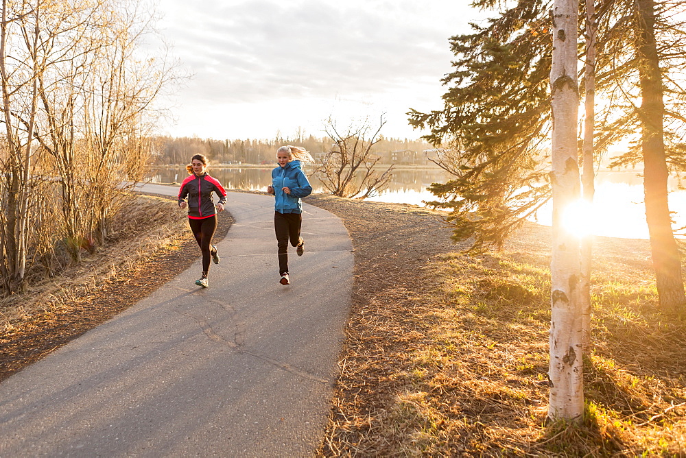 Two young women running on a trail at the water's edge, Anchorage, Alaska, United States of America