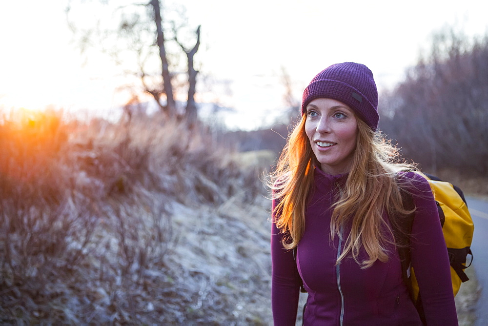 A young women carrying a backpack and walking at sunrise, Anchorage, Alaska, United States of America