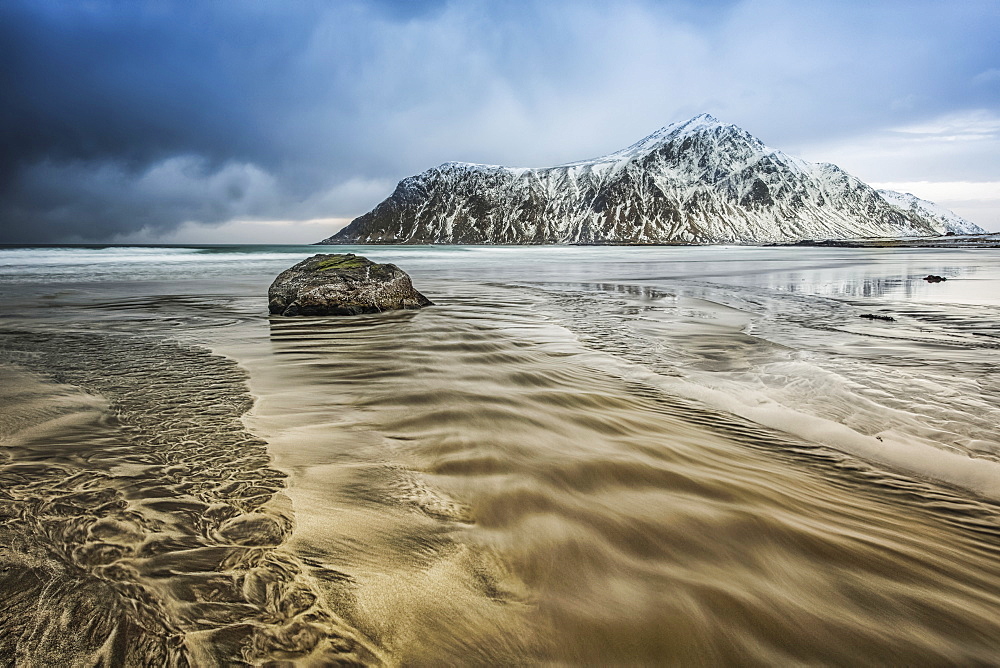 A landscape with rugged mountains and sand along the coastline under a cloudy sky, Nordland, Norway