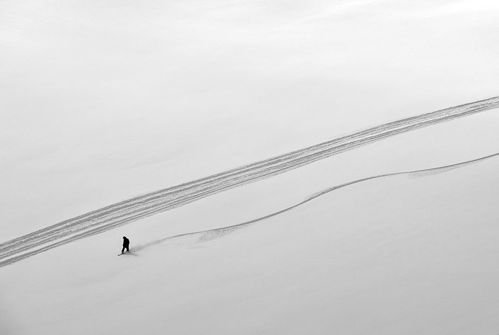 A professional, freeriding snowboarder on a wide open snowy slope making new tracks, British Columbia, Canada