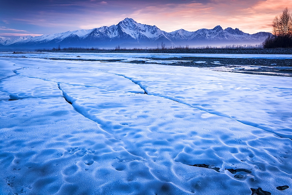 Ice sheet along Matanuska River with a sunset sky and Chugach Mountains in the background, Palmer, Alaska, United States of America