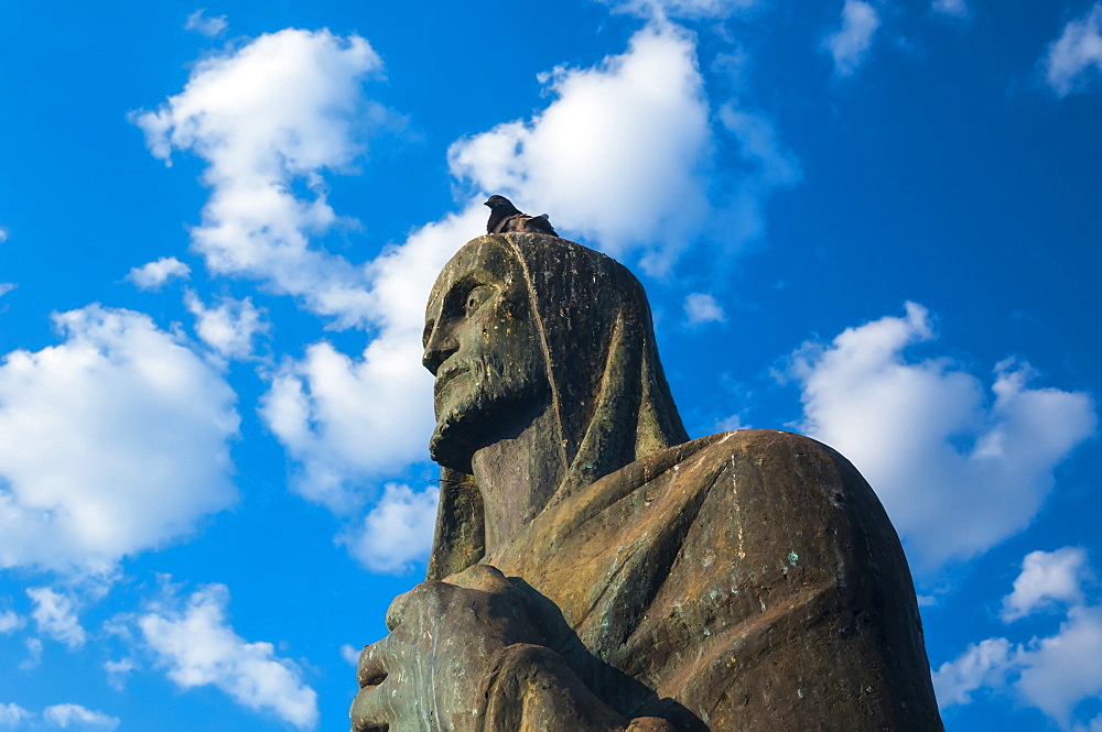 A pigeon sits on the head of an evangelist bronze sculpture outside the Cathedral of Brasilia, Brasilia, Brazil