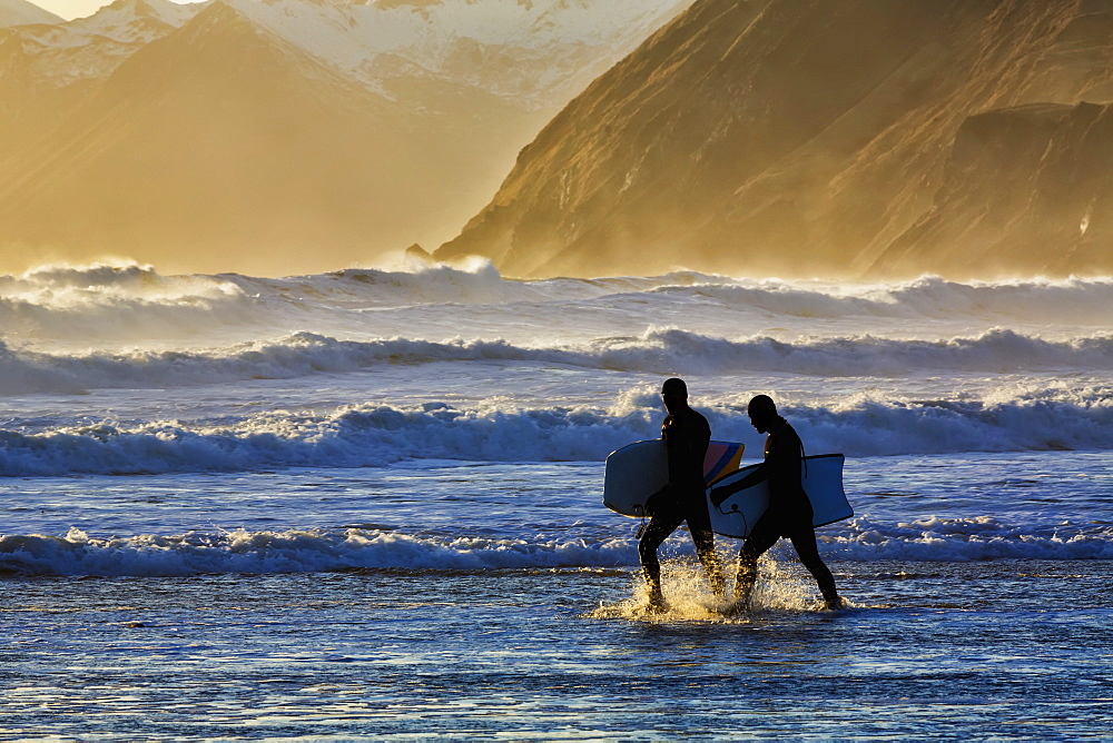 Body Surfers Walk In The Water On The Coast Of Kodiak Island During Late Afternoon, Pasagshak State Park, Kodiak Island, Alaska