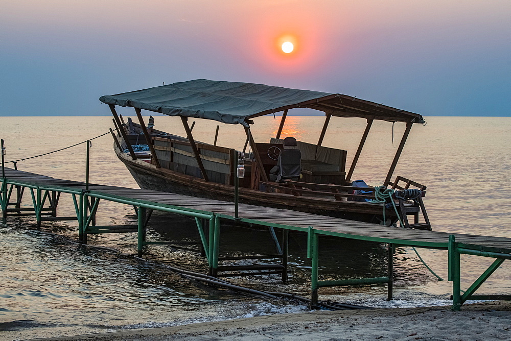 Sun setting behind boat moored to dock at Mbali Mbali Mahale Lodge (Kungue Beach Lodge) on Lake Tanganyika, Tanzania