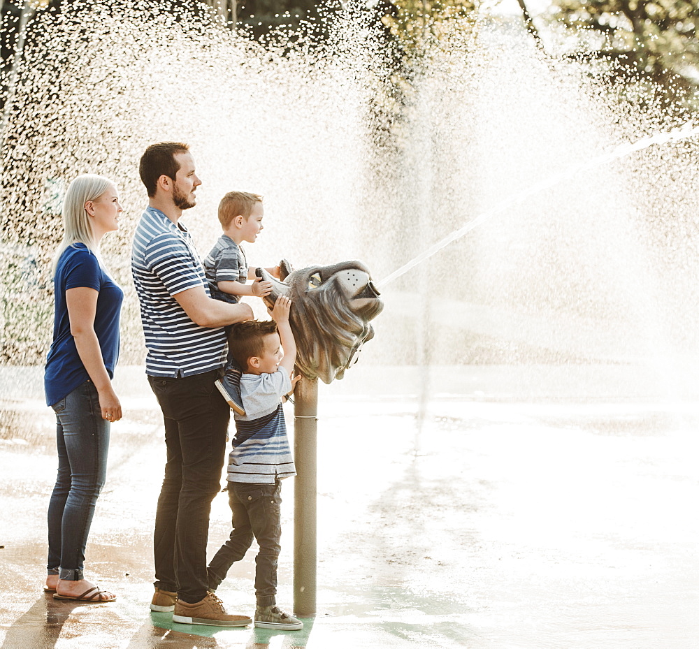 A family with young children playing at a spray park, Edmonton, Alberta, Canada