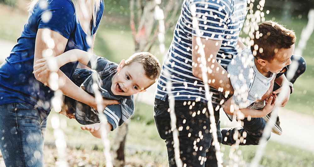 A family with young children playing at a spray park, Edmonton, Alberta, Canada