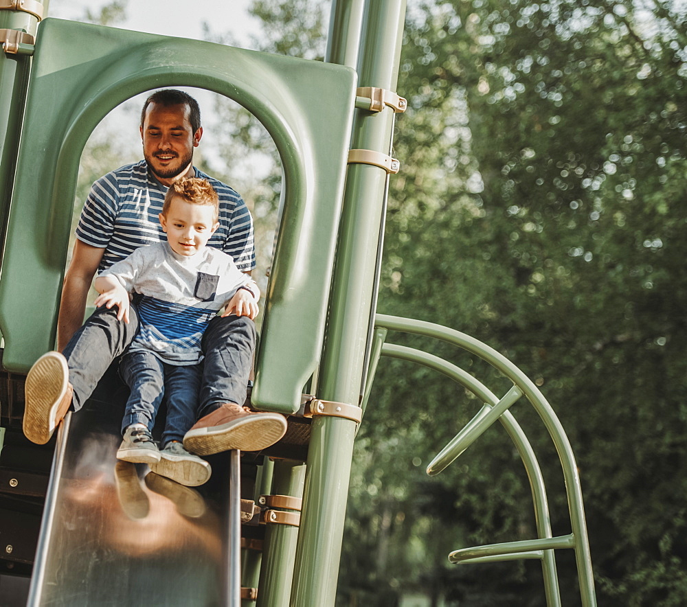 Father on a slide with young son, Edmonton, Alberta, Canada