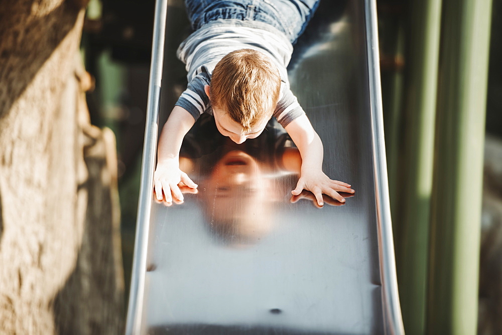 Young boy going down head-first on a playground slide, Edmonton, Alberta, Canada