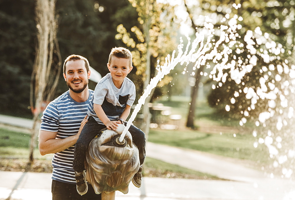 Father and young son at spray park, Edmonton, Alberta, Canada