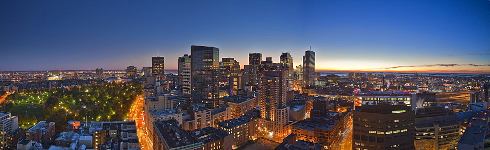 Panoramic view of sunrise in downtown Boston with Boston Harbor, Cambridge and Boston Common and Tremont Street lit up, Boston, Suffolk County, Massachusetts, USA