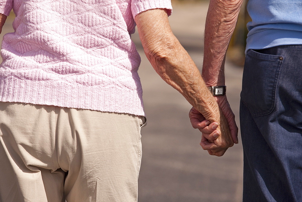 Mid section view of a couple walking with holding hands