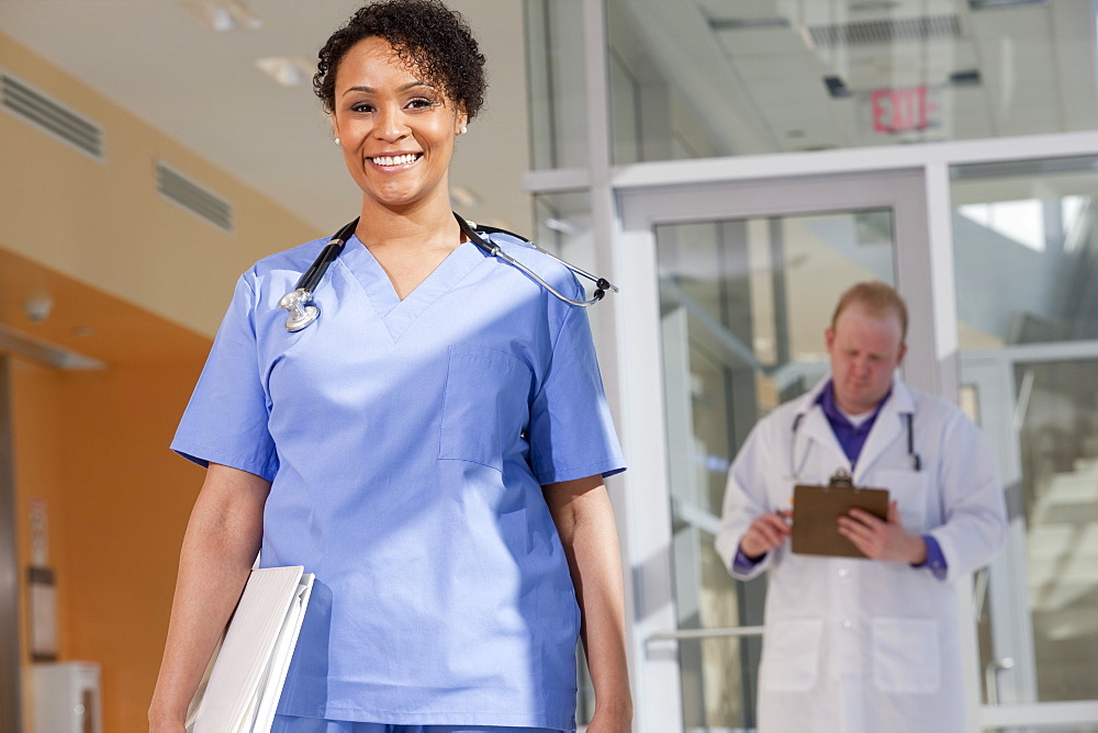 Portrait of a female nurse smiling with a male doctor standing behind her