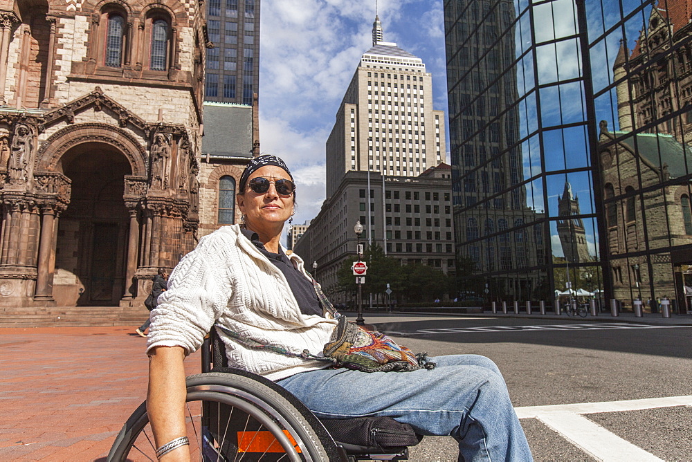 Woman with spinal cord injury crossing street, St. James Avenue, John Hancock Tower, Trinity Church, Boston, Massachusetts, USA