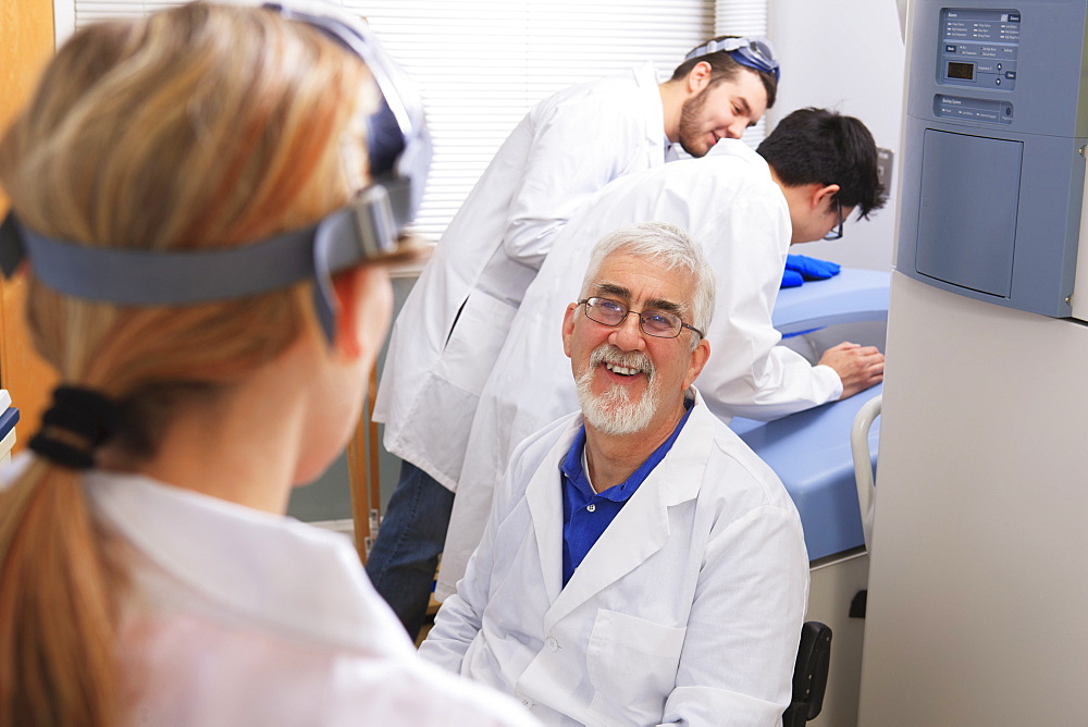 Professor and engineering students discussing bacteria culturing system in a laboratory