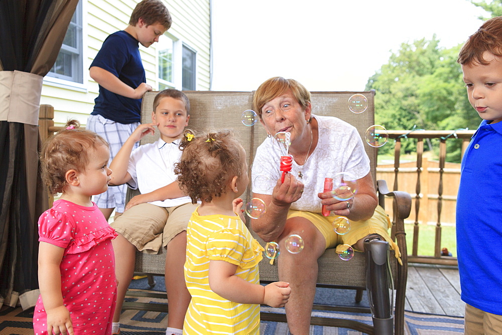 Grandmother with a prosthetic leg blowing bubbles with her grandchildren