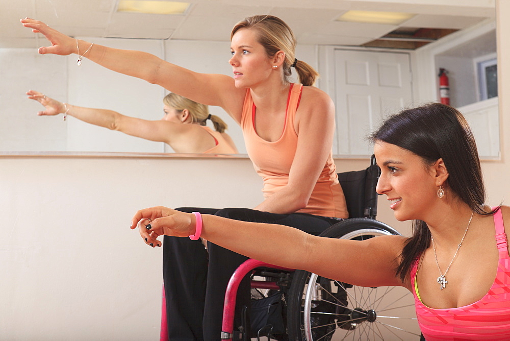 Young women with spinal cord injuries stretching in a yoga studio