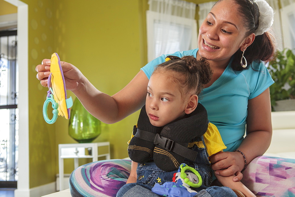 Mother showing small daughter with Cerebral Palsy a toy