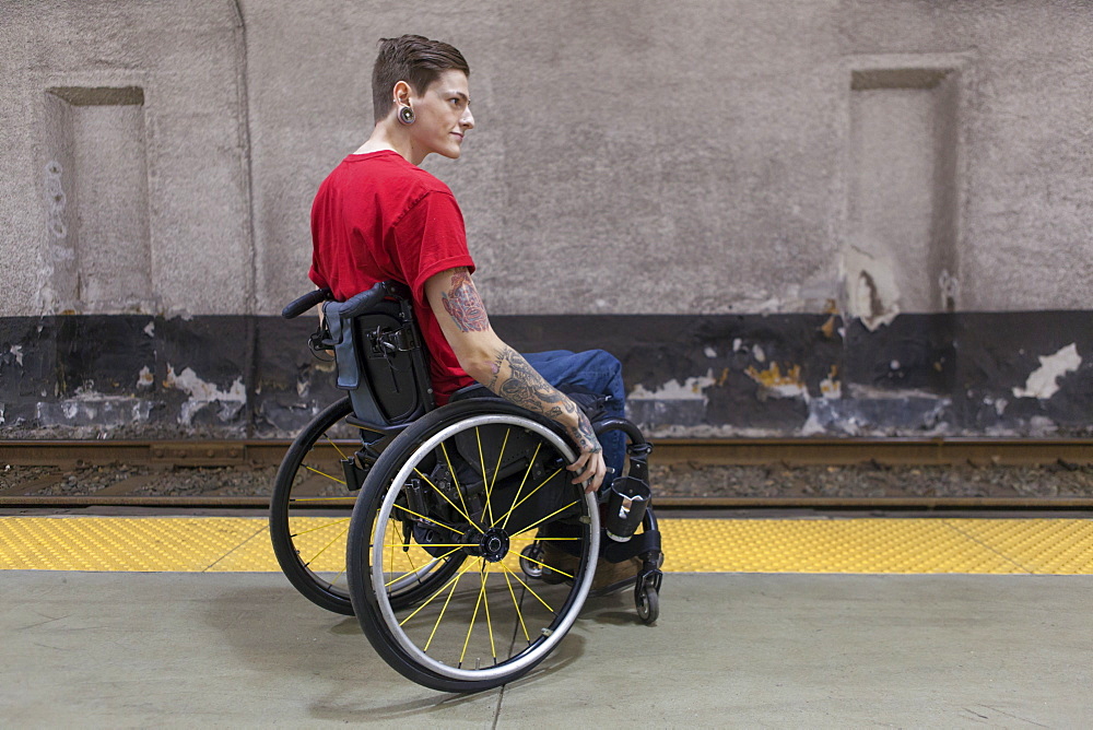 Trendy man with a spinal cord injury in wheelchair waiting for a subway train