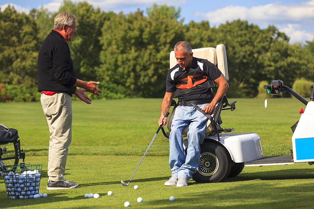 Instructor helping a Man with spinal cord injury to learn golf