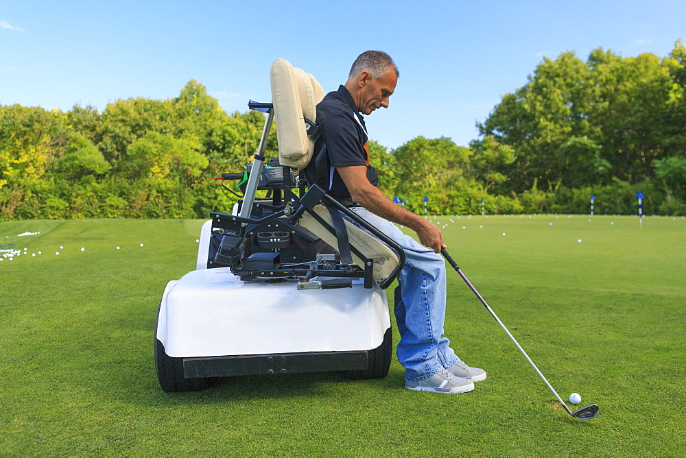 Man with spinal cord injury in an adaptive cart at golf putting green