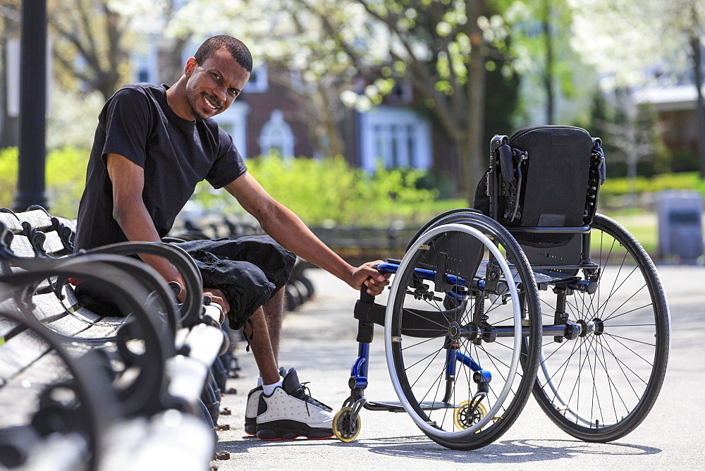 Man who had Spinal Meningitis sitting on a park bench near his wheelchair