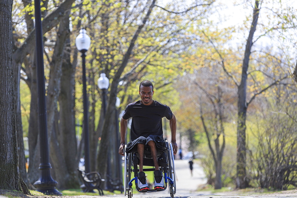 Man in a wheelchair who had Spinal Meningitis going through a park