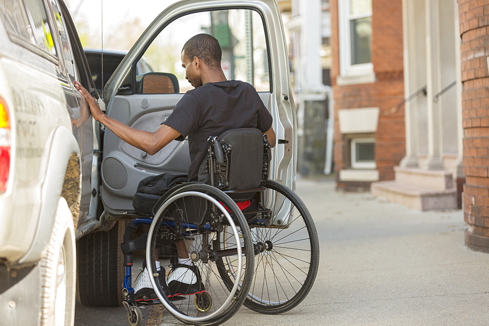 Man in a wheelchair who had Spinal Meningitis entering his accessible vehicle
