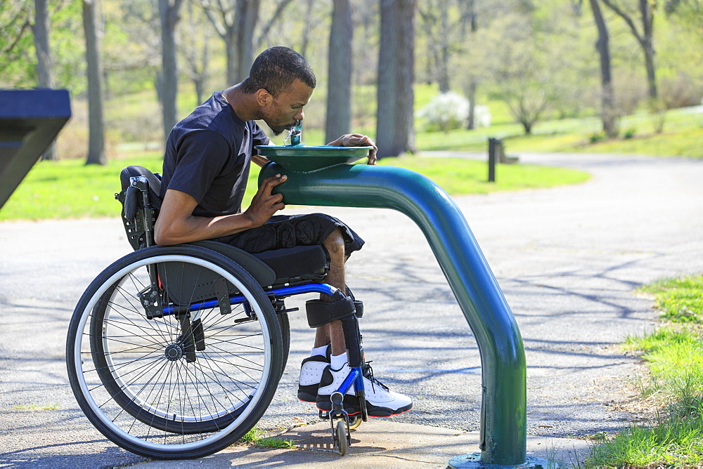 Man in a wheelchair who had Spinal Meningitis using a public water fountain